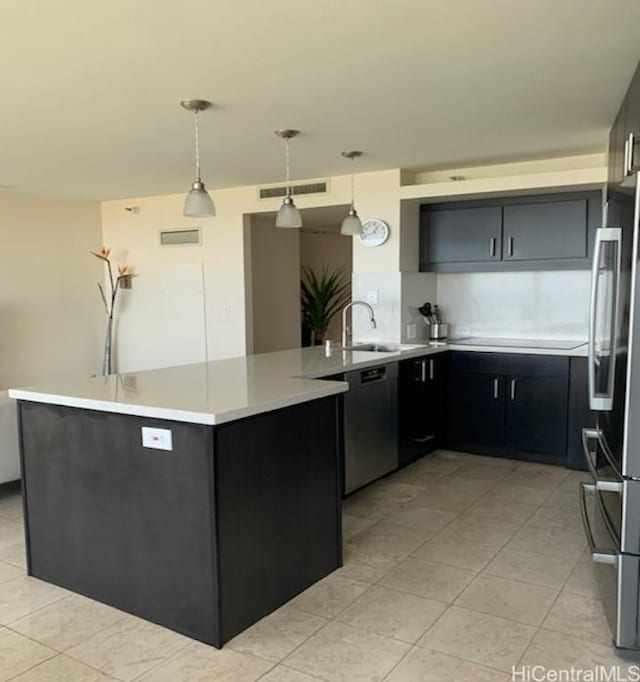 kitchen featuring visible vents, a peninsula, hanging light fixtures, light countertops, and appliances with stainless steel finishes