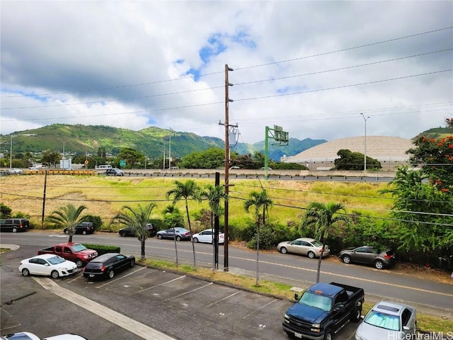 view of parking / parking lot with a mountain view and fence