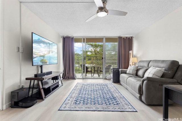 living area with a textured ceiling, wood finished floors, ceiling fan, and a wall of windows