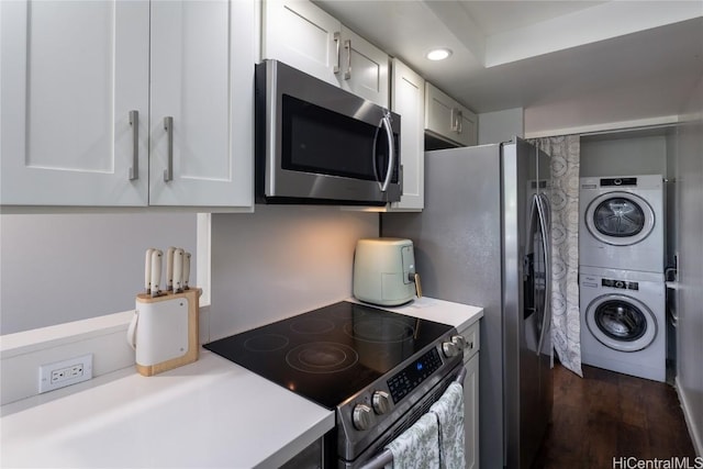 kitchen with stainless steel appliances, white cabinetry, stacked washer and clothes dryer, and light countertops