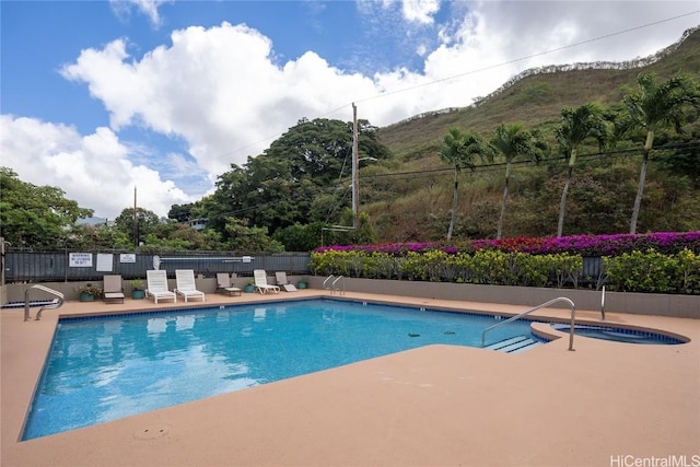 pool featuring a mountain view, a patio, and fence