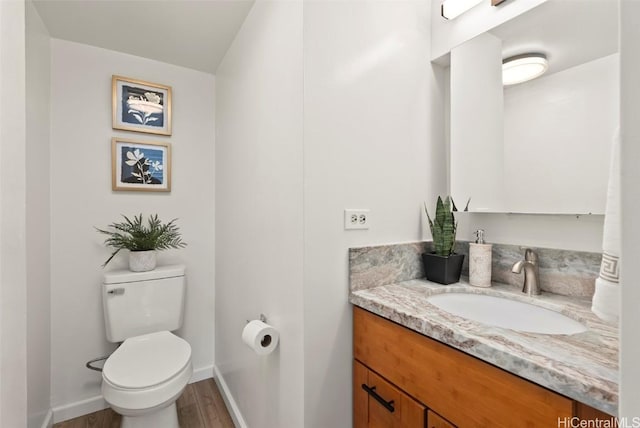 bathroom with baseboards, toilet, wood finished floors, and vanity