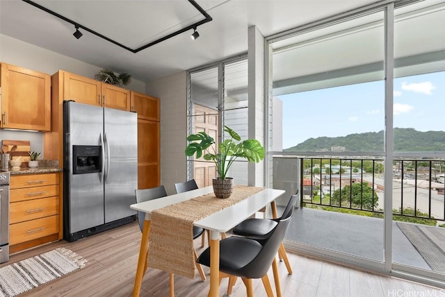 kitchen with stainless steel fridge, rail lighting, light wood-style flooring, and expansive windows