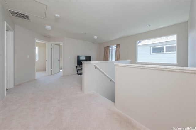 hall with light colored carpet, an upstairs landing, and visible vents