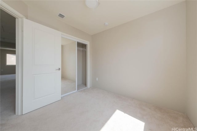 unfurnished bedroom with visible vents, a closet, and light carpet