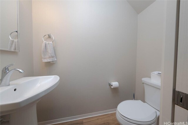 bathroom with a sink, toilet, baseboards, and wood finished floors