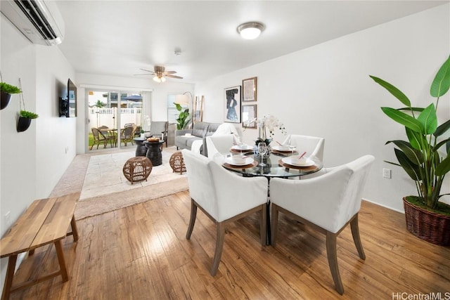 dining room with a wall mounted air conditioner, light wood-type flooring, and a ceiling fan