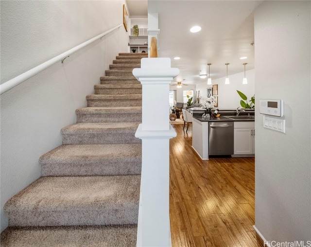 staircase featuring decorative columns, wood-type flooring, and ceiling fan