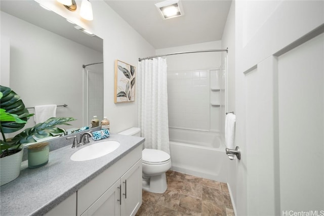 bathroom with stone finish flooring, shower / bath combo with shower curtain, toilet, and vanity