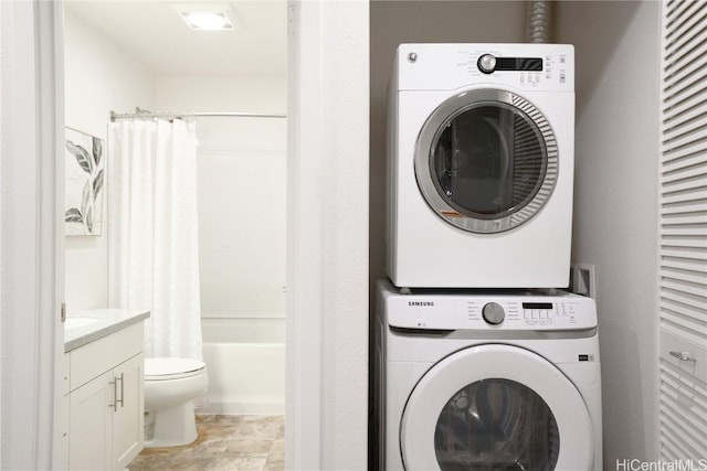 washroom featuring stacked washer / dryer, stone finish floor, and laundry area