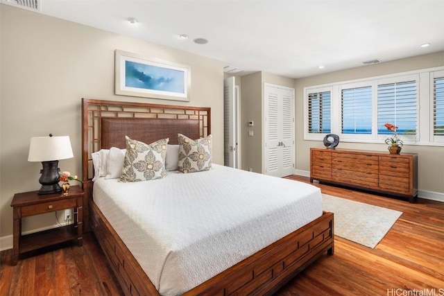 bedroom with a closet, baseboards, visible vents, and wood finished floors