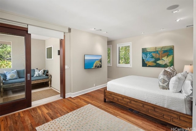 bedroom featuring visible vents, baseboards, and wood finished floors