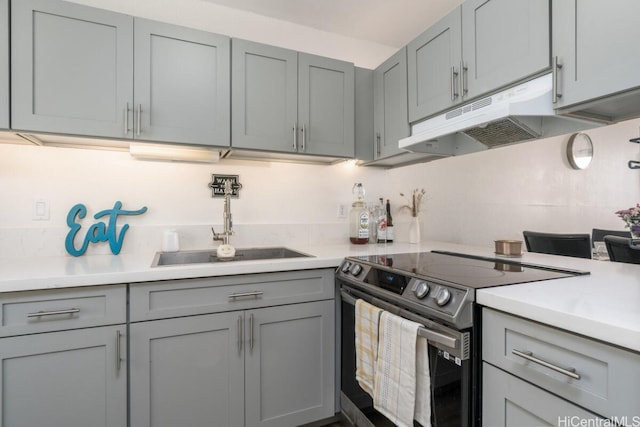 kitchen featuring under cabinet range hood, gray cabinets, and stainless steel electric range