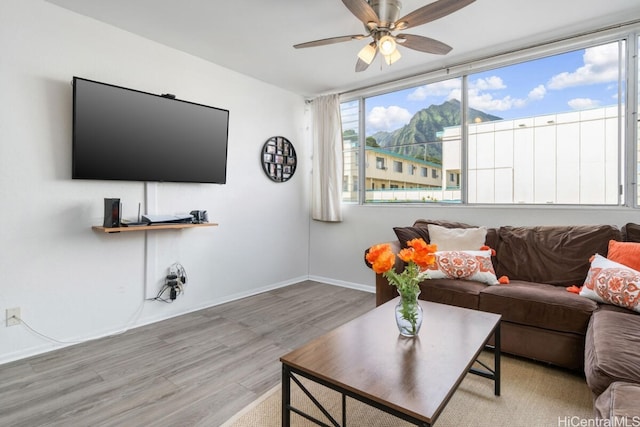 living area with ceiling fan, baseboards, and wood finished floors