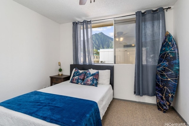 bedroom featuring ceiling fan, a mountain view, a textured ceiling, and carpet