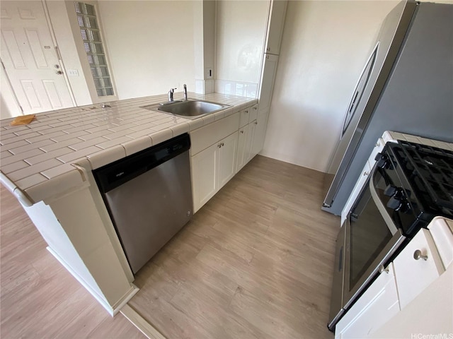 91-241 Hanapouli Cir Unit 24H, Ewa Beach, HI 96706 - kitchen featuring stainless steel dishwasher, range, light wood-style flooring, tile counters, and white cabinetry