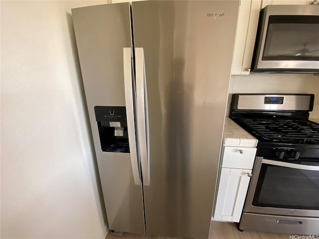 91-241 Hanapouli Cir Unit 24H, Ewa Beach, HI 96706 - kitchen featuring appliances with stainless steel finishes, tile counters, and white cabinets