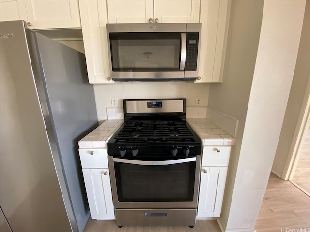 91-241 Hanapouli Cir Unit 24H, Ewa Beach, HI 96706 - kitchen with appliances with stainless steel finishes, tile counters, and white cabinets