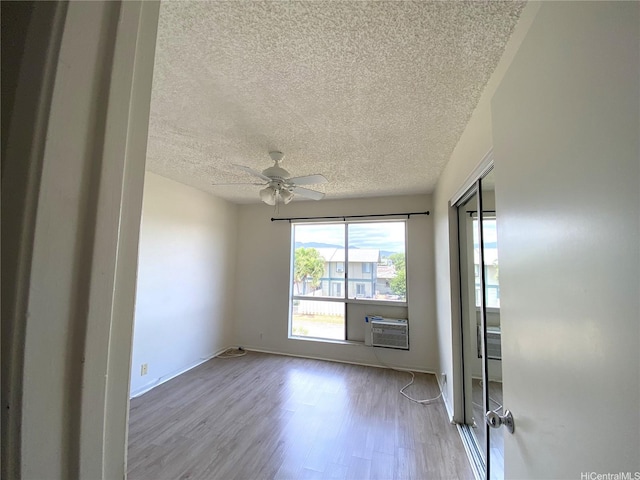 91-241 Hanapouli Cir Unit 24H, Ewa Beach, HI 96706 - spare room with a textured ceiling, wood finished floors, a ceiling fan, and a wall mounted air conditioner