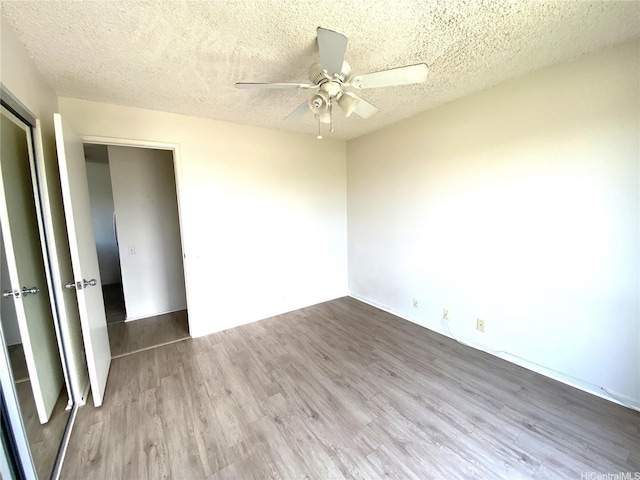 91-241 Hanapouli Cir Unit 24H, Ewa Beach, HI 96706 - spare room with wood finished floors, a ceiling fan, and a textured ceiling