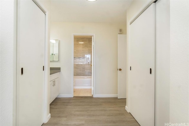 hall with light wood-type flooring and baseboards