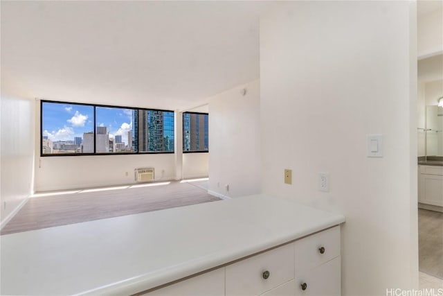 interior space with a wall mounted air conditioner, white cabinets, and light countertops