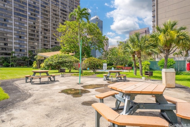 view of home's community featuring outdoor dining area, a patio, and a lawn