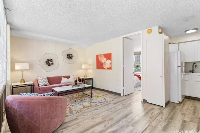 living area with light wood-style floors and a textured ceiling