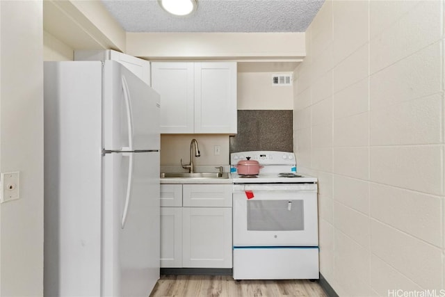 kitchen featuring a sink, white appliances, white cabinets, and light countertops