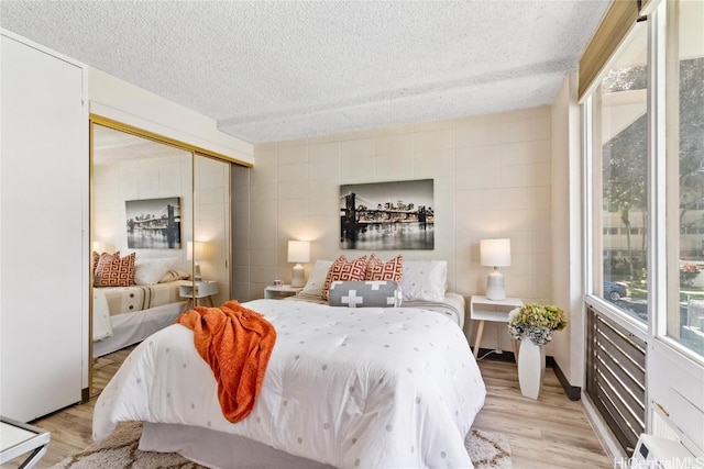 bedroom with a closet, a textured ceiling, and light wood-style flooring