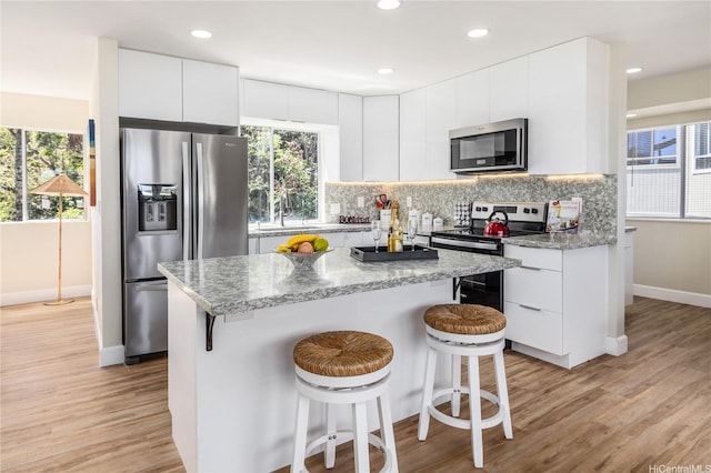 45-081 Lilipuna Rd Unit F, Kaneohe, HI 96744 - kitchen featuring appliances with stainless steel finishes, a kitchen bar, baseboards, light wood finished floors, and recessed lighting