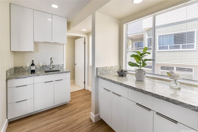 45-081 Lilipuna Rd Unit F, Kaneohe, HI 96744 - kitchen with a sink, baseboards, white cabinetry, light stone countertops, and light wood-style flooring