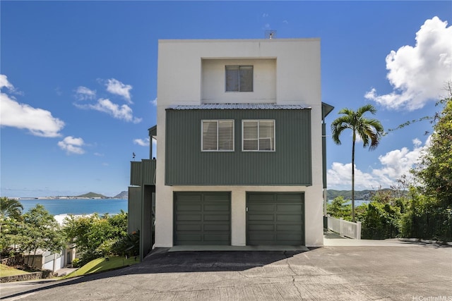 45-081 Lilipuna Rd Unit F, Kaneohe, HI 96744 - view of front facade featuring an attached garage, driveway, a water view, and stucco siding
