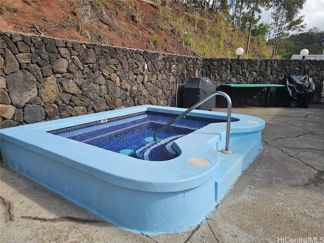 view of swimming pool with area for grilling and an in ground hot tub