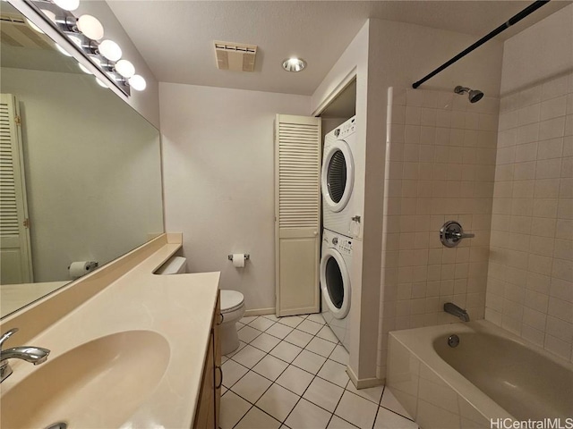 bathroom featuring tile patterned flooring, stacked washer / dryer, visible vents, baseboards, and toilet