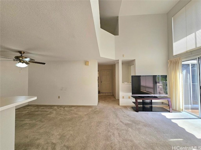 unfurnished living room with carpet, a high ceiling, ceiling fan, and a textured ceiling