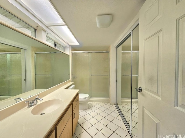 bathroom with vanity, tile patterned floors, toilet, and a shower stall