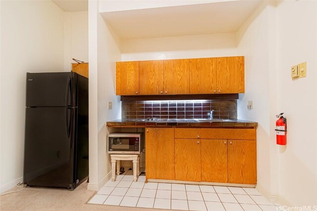 1088 Bishop St Unit 204, Honolulu, HI 96813 - kitchen with brown cabinets, backsplash, tile counters, and freestanding refrigerator