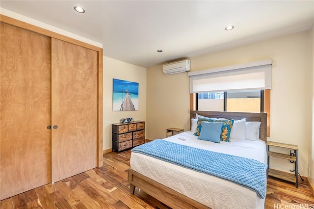 bedroom featuring recessed lighting, an AC wall unit, and wood finished floors