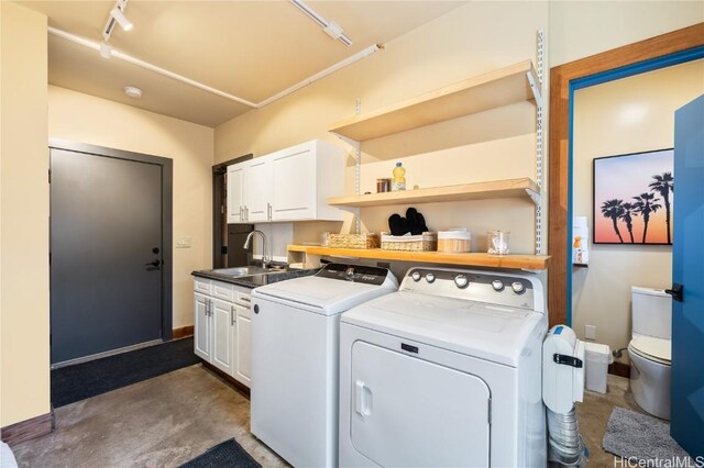 laundry room featuring a sink, washing machine and dryer, cabinet space, rail lighting, and baseboards