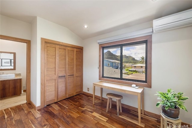 home office with dark wood-type flooring, a wall mounted AC, a sink, baseboards, and vaulted ceiling