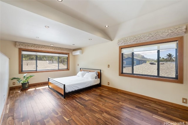 bedroom with a wall unit AC, recessed lighting, wood finished floors, and baseboards