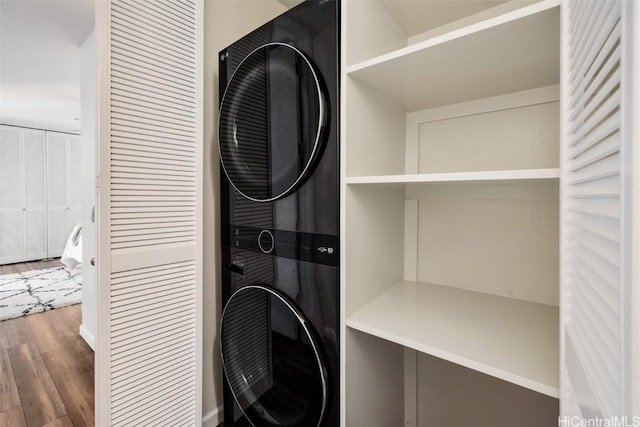 laundry room featuring laundry area, stacked washer / dryer, and wood finished floors