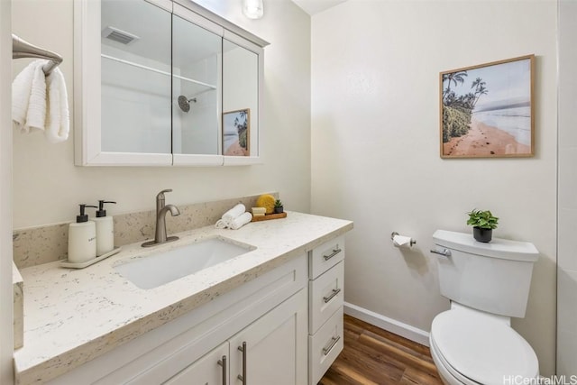 bathroom featuring vanity, wood finished floors, visible vents, baseboards, and toilet