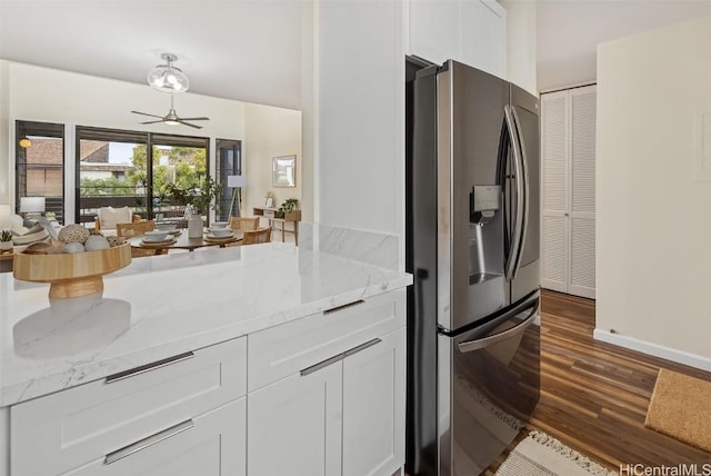 kitchen featuring ceiling fan, light stone countertops, stainless steel refrigerator with ice dispenser, dark wood-style floors, and white cabinetry