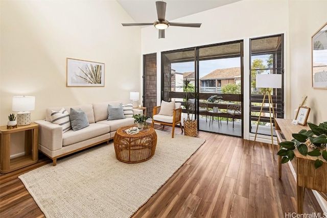 living room with ceiling fan, a high ceiling, and wood finished floors