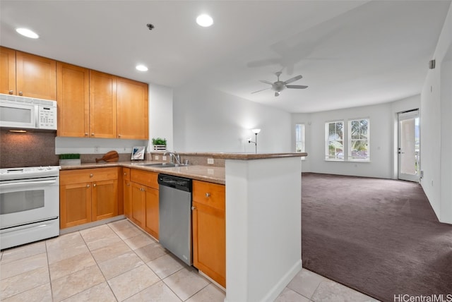 kitchen with a sink, open floor plan, white appliances, a peninsula, and light colored carpet