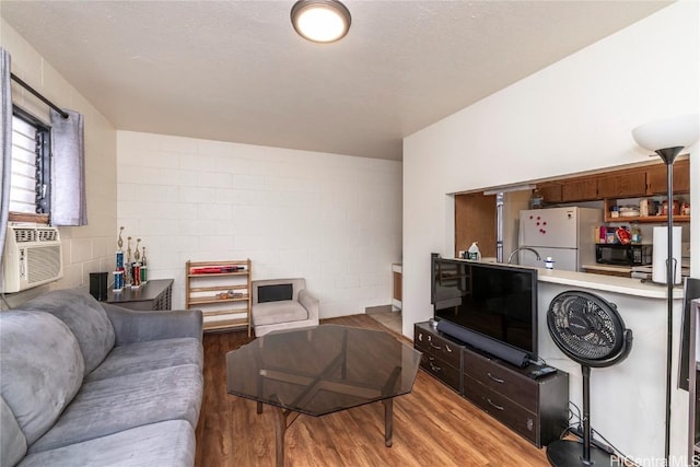 living room featuring light wood finished floors, a textured ceiling, and concrete block wall