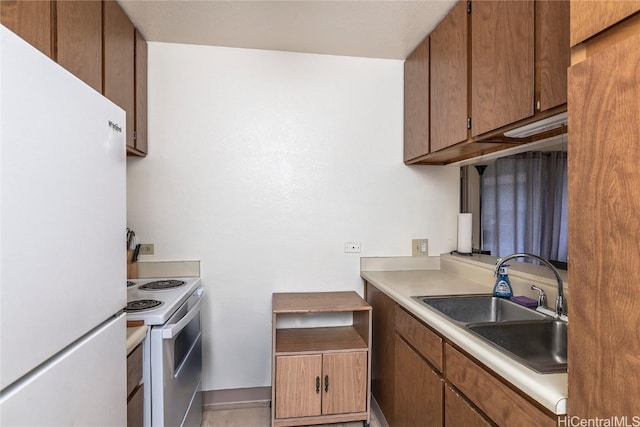 kitchen featuring brown cabinets, white appliances, light countertops, and a sink