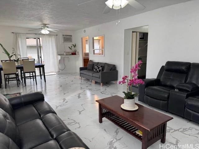 living room with marble finish floor, a textured ceiling, a wall mounted AC, and a ceiling fan